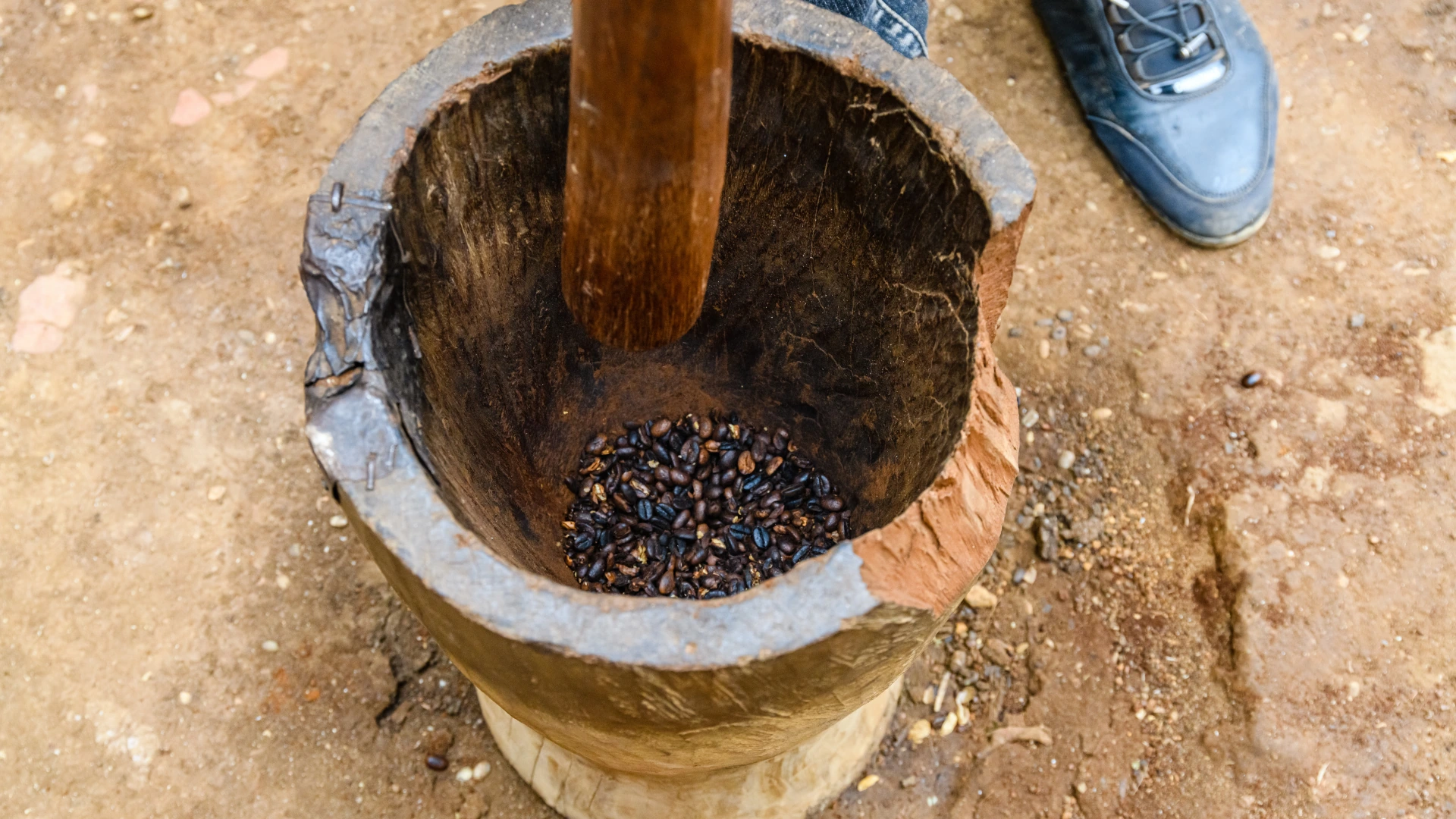 Roasted coffee beans in a traditional wooden mortar