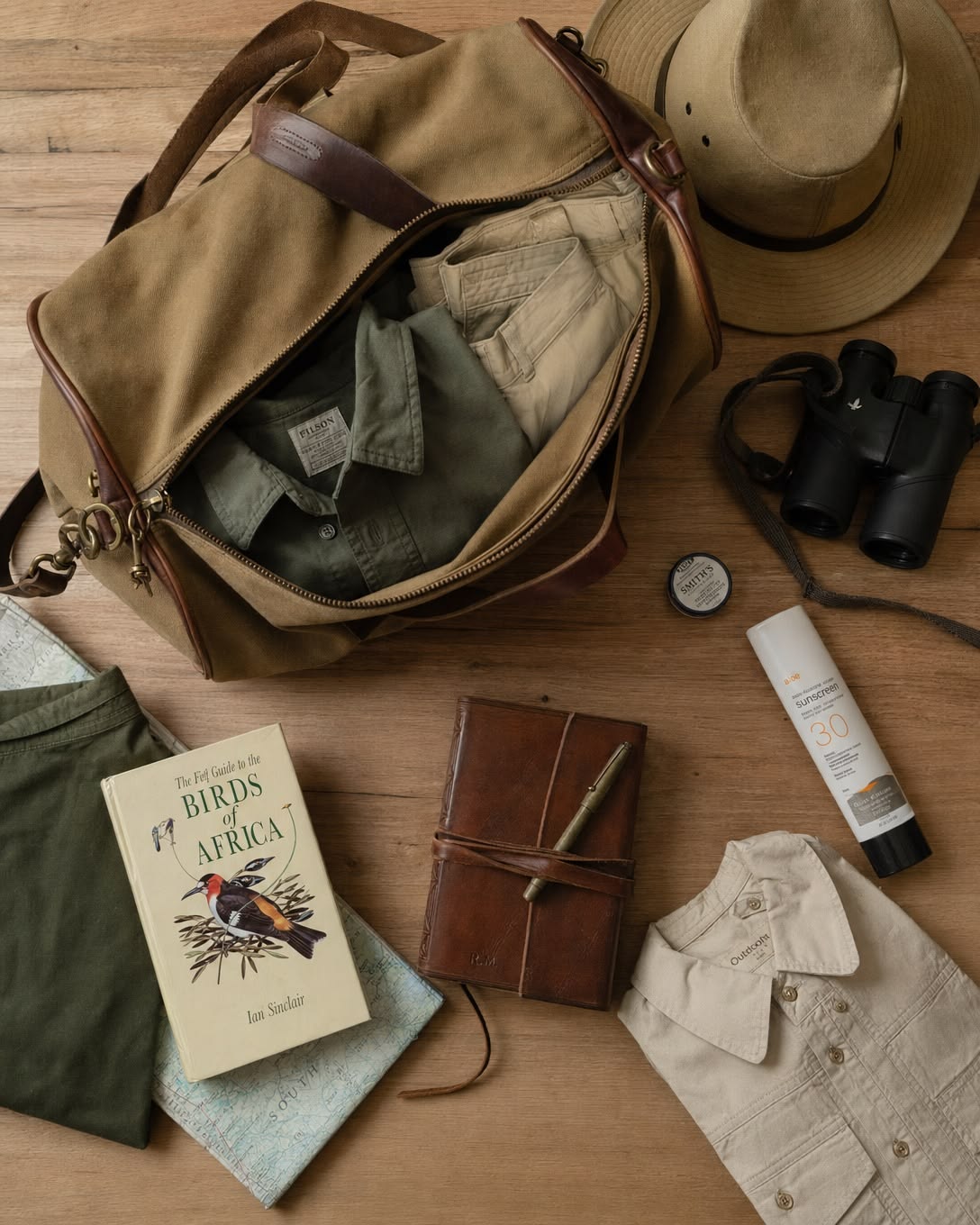 Safari clothing, binoculars, a hat and travel essentials packed for a journey