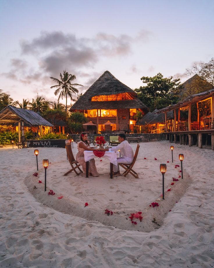 A couple sharing a candlelit dinner on the beach